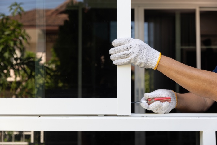 White‑gloved person opens a window with a knife during sliding glass door installation in Jacksonville